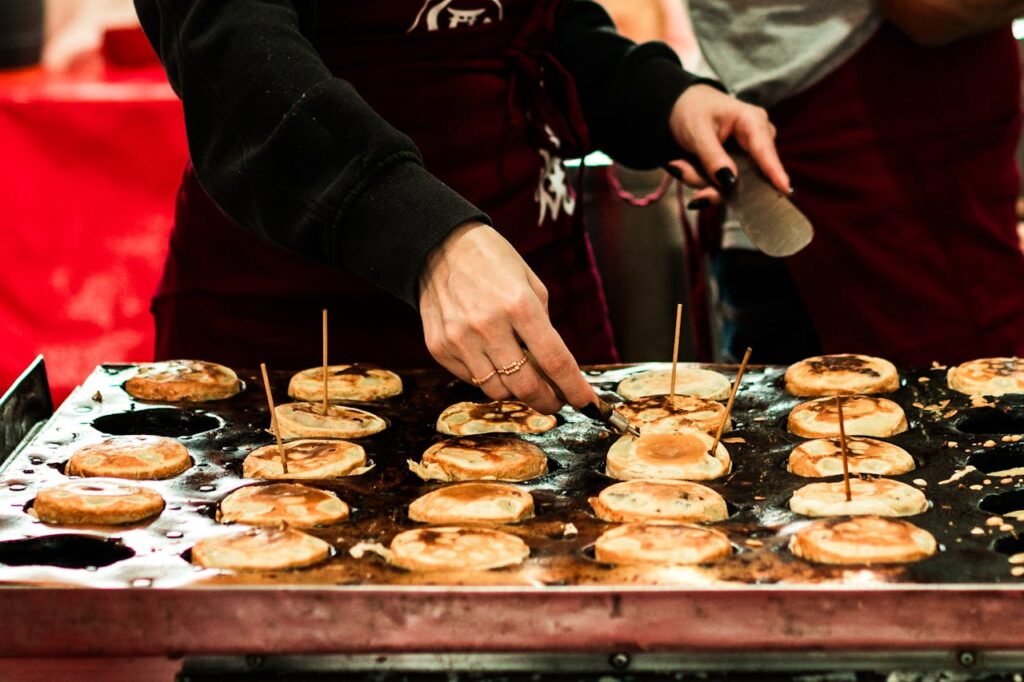 A street food vendor in São Paulo preparing traditional pancakes on a hot griddle.