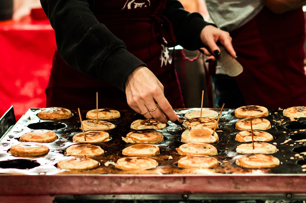 A street food vendor in São Paulo preparing traditional pancakes on a hot griddle.